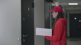 A pizza delivery man in red uniform brought two boxes to a young girl. Cash transfer for delivery. Happy girl buys pizza. Modern supply of goods. 4k video.