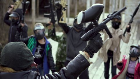 Madman strike warm man into armed rebellion. Group of masked paintball with weapon in their hand close up begin aggressive 4K strike. Evil people in helmet pick up paintball guns anarchist revolution.