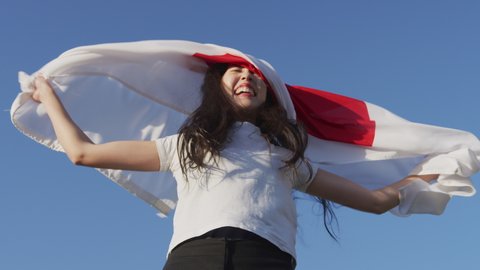 Proud Japanese girl supporter holding Flag of Japan, funny moment near the end where flags hits her in the face. Shot on Red Camera. Slow motion. Patriot and sports fan concepts. Blooper reel.