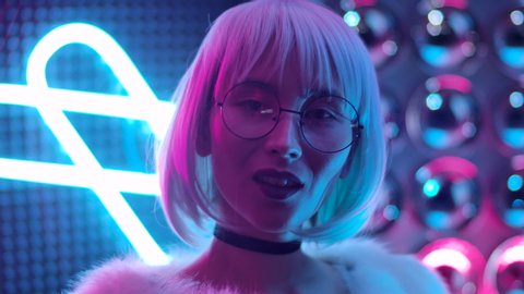 Portrait Beautiful Trendy Girl In Glasses Looking At Camera and Smile. Confident and Attractive Woman with Open Eyes in Purple Blue Light Posing at Party. Cute 20s Female Closeup in Colourful Pink 4K