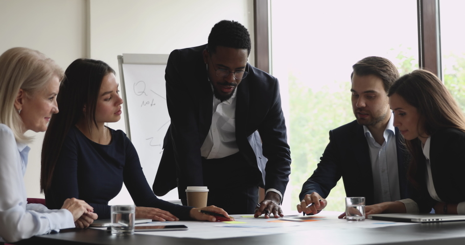 Focused african male manager executive mentor and multiethnic team analyze paperwork discuss project plan share ideas brainstorm work together in teamwork at table office group corporate meeting Royalty-Free Stock Footage #1039082276