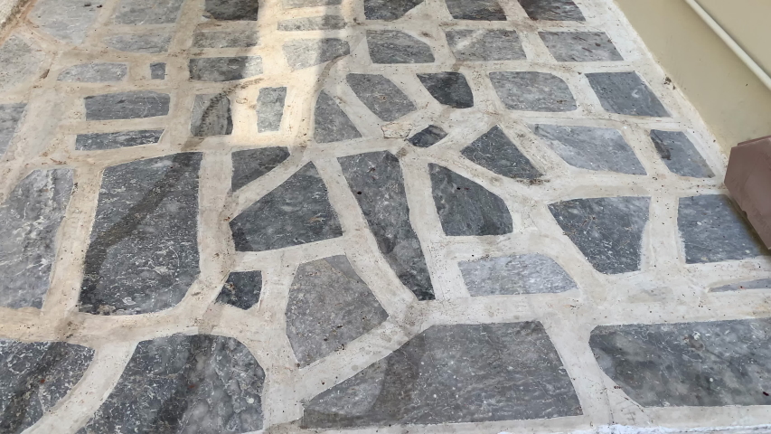 Typical Greek alley in the city center. Narrow street alley with stairs. Stone tiles on the floor.