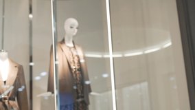 A female shopper walks up to the window and looks at a stylishly dressed mannequin in a trendy boutique in the Mall. Buying and selling concept