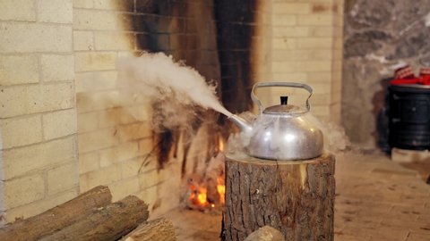 Boiling retro aluminium kettle. Teapot steams. Santa Claus takes a boiling kettle. Closeup. Teapot on a log. New year spirit. Christmas eve.