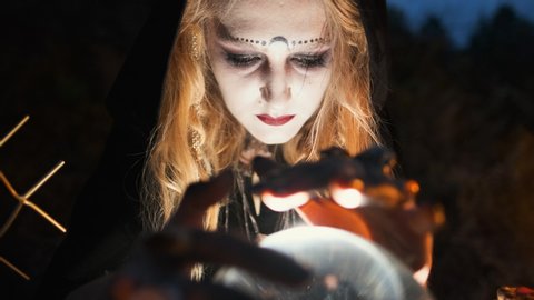 Young Witch Fortune-Tellers In The Forest. She Sits On A Table And Wonders Over A Glass Layer. On The Table Attributes For Witch-Mirror, Layer, Potion.: stockvideo