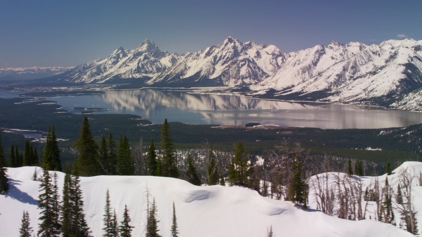 Grand Teton National Park, Rocky Mountains, Wyoming. Aerial view of beautiful snow covered mountain peaks and Jackson Lake. Shot from helicopter with Shotover gimbal and RED 8K camera.