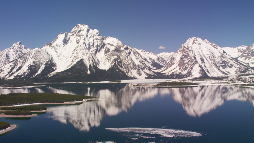 Grand Teton National Park, Rocky Mountains, Wyoming. Aerial view of beautiful snow covered mountain peaks and Jackson Lake. Shot from helicopter with Shotover gimbal and RED 8K camera.
