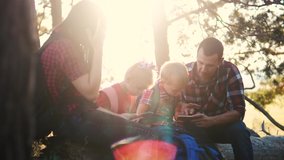 happy family search navigation on a digital tablet tourists teamwork slow motion video concept. mom dad son and daughter on a smartphone looking for a way hiking in the forest looking for a way on a
