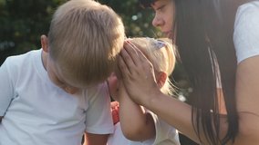 happy family mom tells her son a secret. little girl whispers a secret in the boy s ear. children tell a secret. childhood game concept lifestyle slow motion video