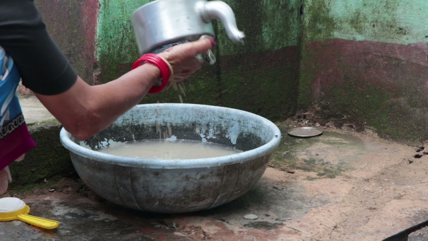 A village woman washing utensil in open