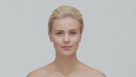 Studio portrait of young, beautiful and natural blond woman applying skin care cream. Face lifting, cosmetics and make-up.
