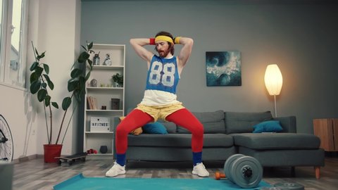 LOS ANGELES, CALIFORNIA, 10 OCTOBER, 2019: Sexy aggressive young man in retro sportswear dancing with seducing moves on exercise mat on training at home.