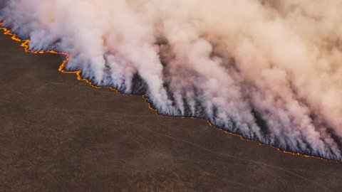 Climate emergency.Climate change. Global warming. Epic spectacular high aerial fly over view of a grass fire in the Okavango Delta, caused by drought and climate change, Southern Africa