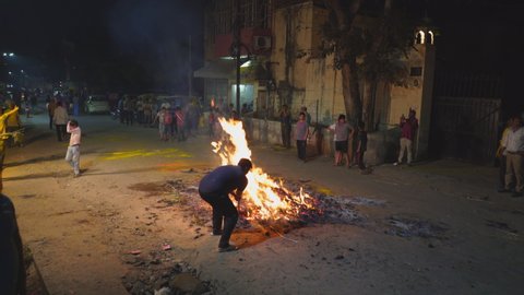 JAIPUR, INDIA - MARCH 20, 2019: a hindu man scoops burning coals from a holi eve bonfire in jaipur, india