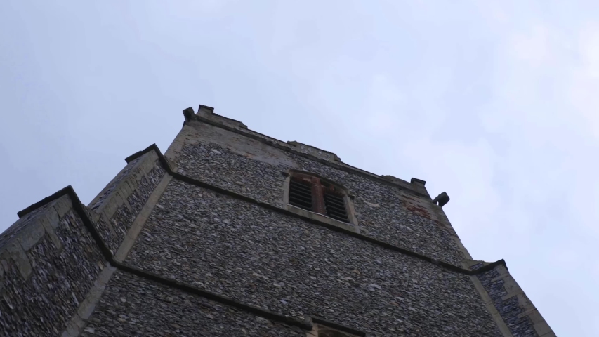 Panning down from English church tower to ornate window.