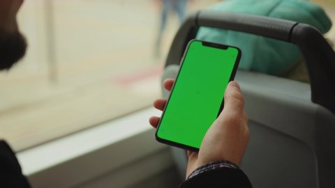 NEW YORK - May 19, 2019: Man young hand uses holding a mobile telephone with a vertical green screen in tram chroma key smartphone technology cell phone street touch message display