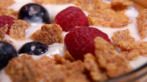 Healthy breakfast: raspberries and blueberries fall on cereal yogurt