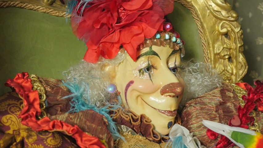 Harlequin sits and smiles on a chair
