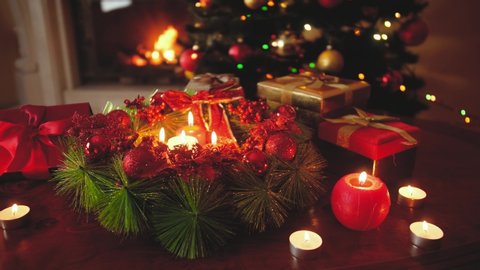 4k video of beautiful decorated advent wreath with burning candles against glowing Christmas tree. Perfect background or backdrop for Christmas or New Year