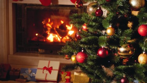 4k footage of big heap of gifts and present next to burning fireplace and glowing Christmas tree in living room on Christmas eve
