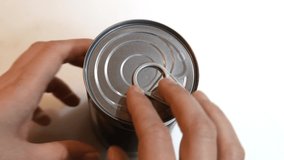 Opening a can of baked beans. British comfort food. Haricot beans, also known as navy beans, in tomato sauce in aluminum tin. Hand appearing opening can.