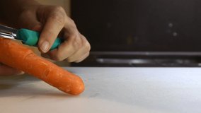 Kitchen food prep video, peeling some fresh orange carrots. White female preparing food for a meal. Healthy vegetarian, vegan food. Left handed woman peeling carrot.