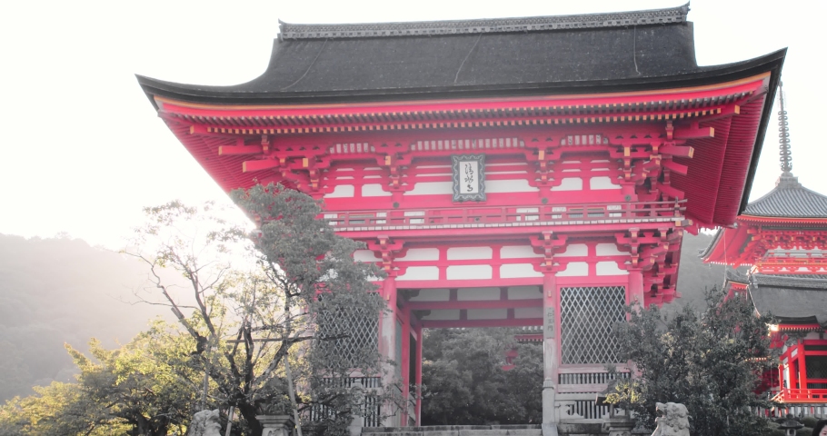 Slide shot of the sunrise appearing from behind a shrine in Kyoto, Japan 4K slow motion