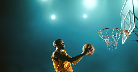 Basketball player makes a slam dunk during a game. He wears unbranded sport clothes.