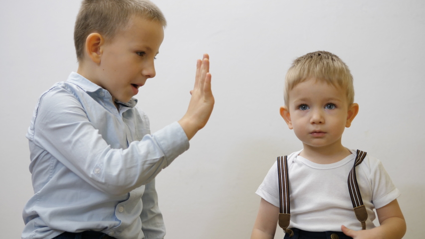 Portrait of elegant children give five, bigger brother arrange baby suspenders