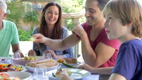 Camera pans around table as multi-generation family enjoy meal together.Shot on Canon 5d Mk2 with a frame rate of 30fps