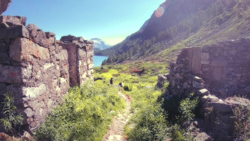 Stone ruins on the hiking trail, mountaineer walking on the green valley, spring landscape. 4k