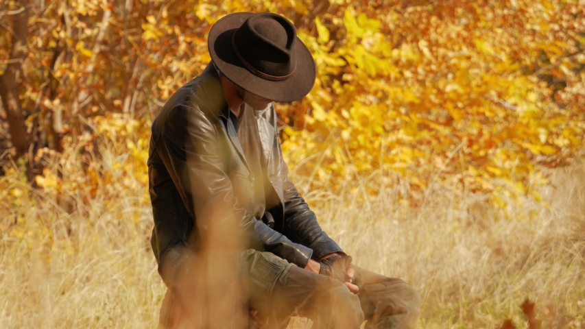 Secretive man sits in the autumn forest and sleeps