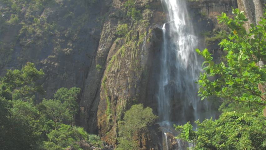 Pictorial large waterfall surrounded by high rocky cliffs and green trees on sunny summer day slow motion. Concept wildlife nature | Shutterstock HD Video #1039226582