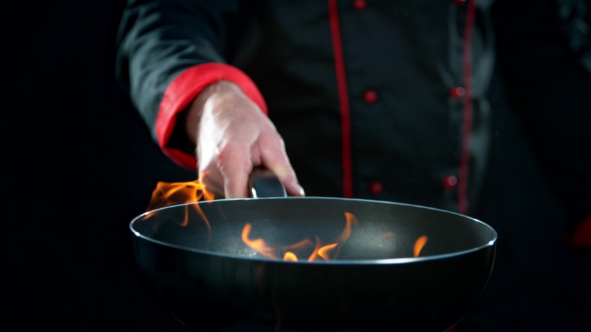 Super Slow Motion Shot of Chef Holding Frying Pan and Falling Chilli Peppers into Fire at 1000fps. Royalty-Free Stock Footage #1039227434