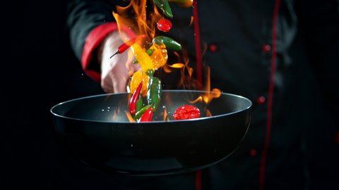 Super Slow Motion Shot of Chef Holding Frying Pan and Falling Chilli Peppers into Fire at 1000fps.