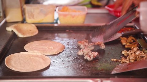 Meat is fried and wheat tortillas are warmed for traditional Mexican tacos
