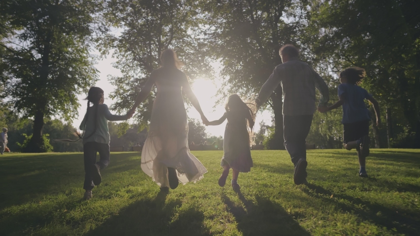 Silhouetted happy caucasian family running towards sun having fun in city park at sunset. Slow Motion. Family, Motherhood, childhood, freedom, future and travel concept. Brother, sisters and parents | Shutterstock HD Video #1039232021