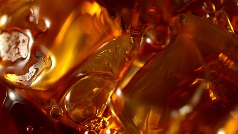 Super Slow Motion Macro Shot of Pouring Whiskey into Glass with Ice Cubes at 1000fps.