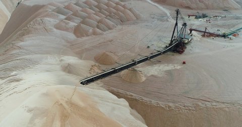 Salt piles, aerial view of industrial quarries, conveyor in salt pits, mining of salt, conveyor line in working process, view from height.