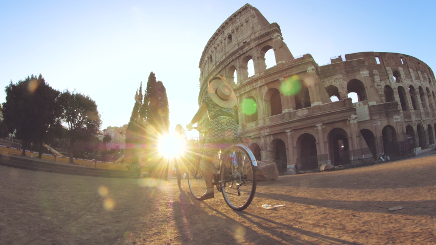 Three happy young women friends tourists riding bikes at Colosseum in Rome, Italy at sunrise. Royalty-Free Stock Footage #1039238696