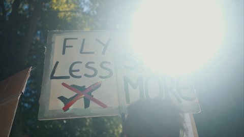 A placard reading 'fly less strike more' at a climate change pretest