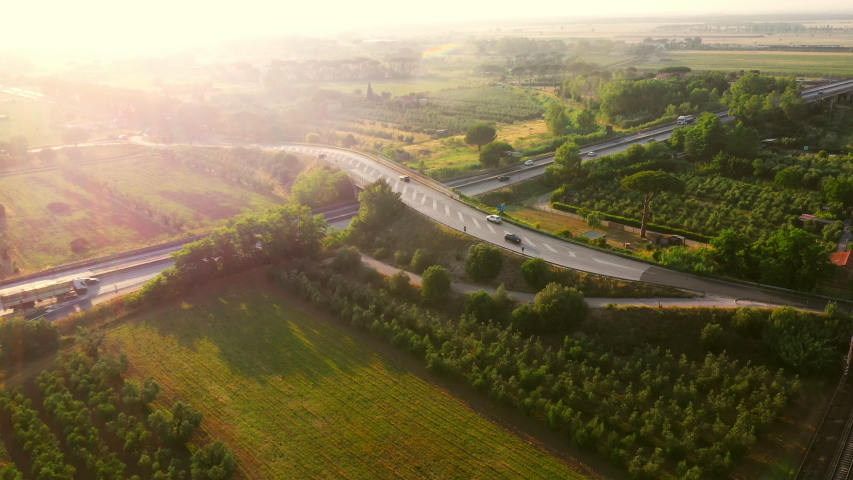 Aerial Drone Footage: Long Haul Semi Trucks Driving on the Busy Highway in the Rural Region of Italy. Beautiful Scenery of Nature and Human Logistics Progress Royalty-Free Stock Footage #1039245347