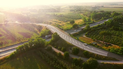 Aerial Drone Footage: Long Haul Semi Trucks Driving on the Busy Highway in the Rural Region of Italy. Beautiful Scenery of Nature and Human Logistics Progress