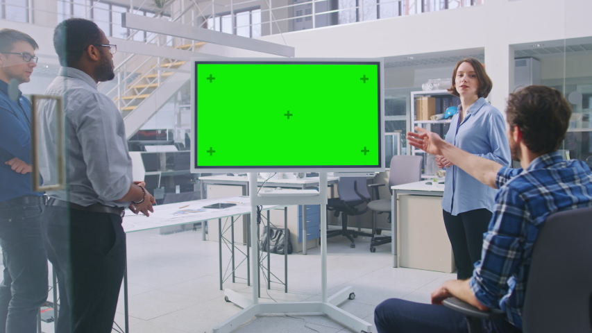 Female Specialist Leads Briefing, Talks and Draws on Digital Interactive Whiteboard Showing Green Mock-up Screen. Industrial Design Facility Team of Engineers and Technicians have a Meeting, | Shutterstock HD Video #1039247906