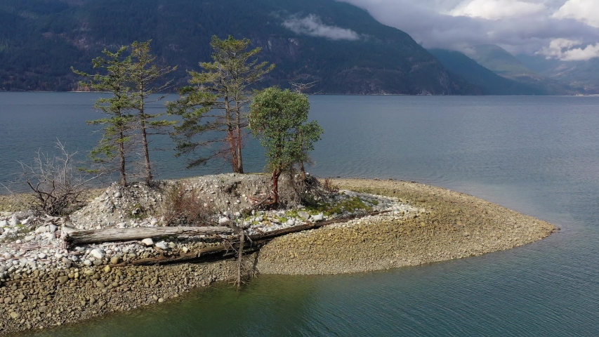 Aerial view over inlet, ocean and island with boat and mountains in beautiful British Columbia. Canada. 4K.