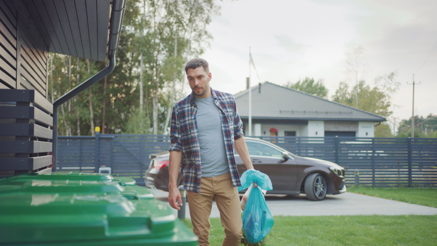 Caucasian Man is Walking Outside His House in Order to Take Out Two Plastic Bags of Trash. One Garbage Bag is Sorted into Biological Food Waste, Other is Thrown into Recyclable Bottles Garbage Bin. | Shutterstock HD Video #1039252367