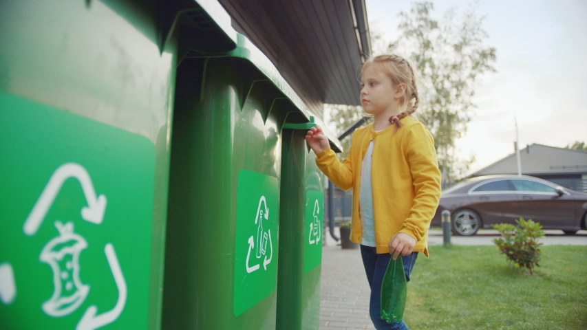 Young Girl is Walking Outside Her House in Order to Throw Away an Empty Plastic Bottle into a Trash Bin. She Uses Correct Garbage Bin Because This Family is Sorting Waste and Helping the Environment. | Shutterstock HD Video #1039252394
