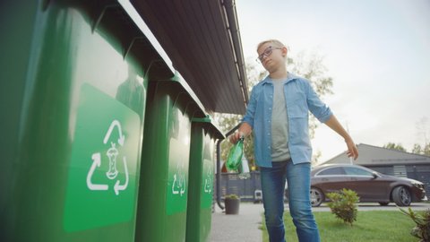 Young Boy is Walking Outside His Home in Order to Throw Away Two Empty Plastic Bottles into a Trash Bin. He Uses Correct Garbage Bin Because This Family is Sorting Waste and Helping the Environment.