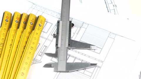 Metal calliper and part of yellow folding rule on the building plan, scheme, background, rotation