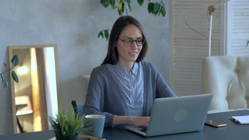 Beautiful woman typing on laptop, working in office, looking to the camera and smile. Medium shoot. | Shutterstock HD Video #1039267655